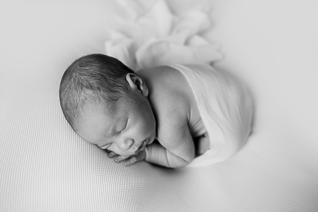 cute newborn baby boy wrapped in white for newborn photo shoot in memphis