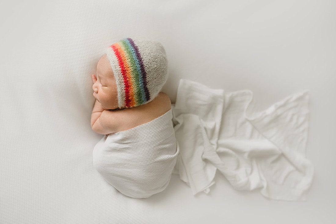 rainbow baby boy wearing rainbow bonnet for newborn photo shoot in memphis