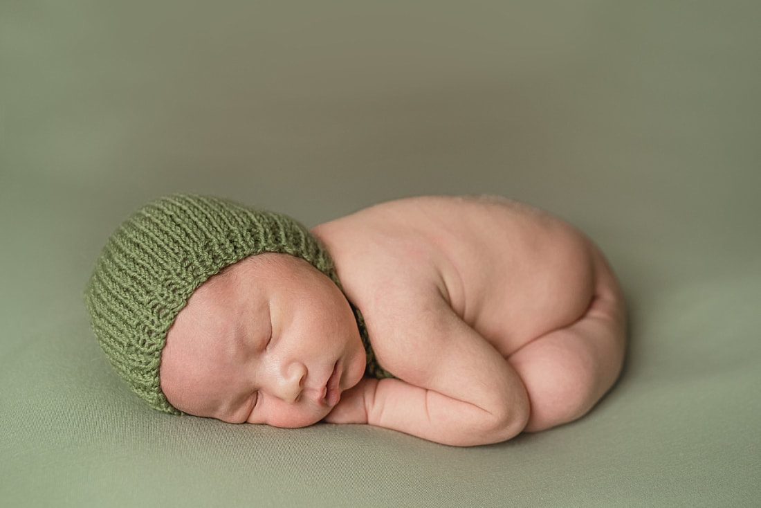 adorable newborn baby boy wearing green bonnet during newborn photo shoot in memphis