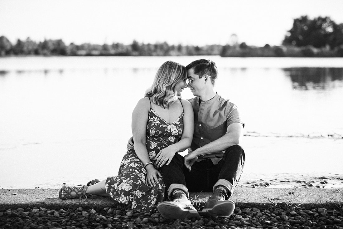 couple posing for engagement photos by the lake at shelby farms park in memphis, tn