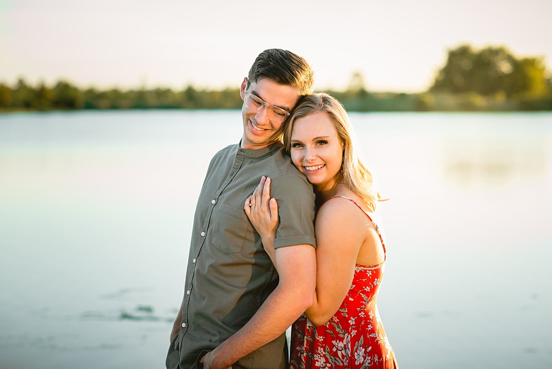 couple posing for engagement photos by the lake at shelby farms park in memphis, tn