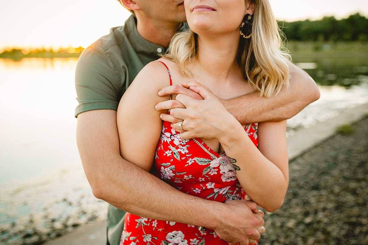 couple posing for engagement photos by the lake at shelby farms park in memphis, tn