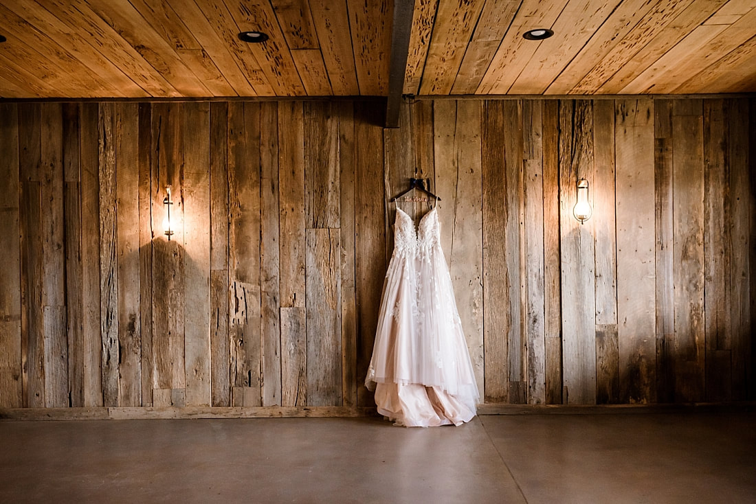 wedding dress hanging on the old rustic barn wall of green frog farm