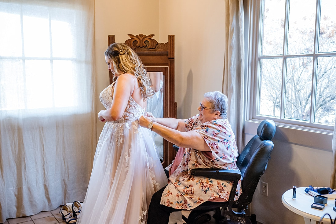 bride's mother helping bride into her wedding dress at Green Frog Farm