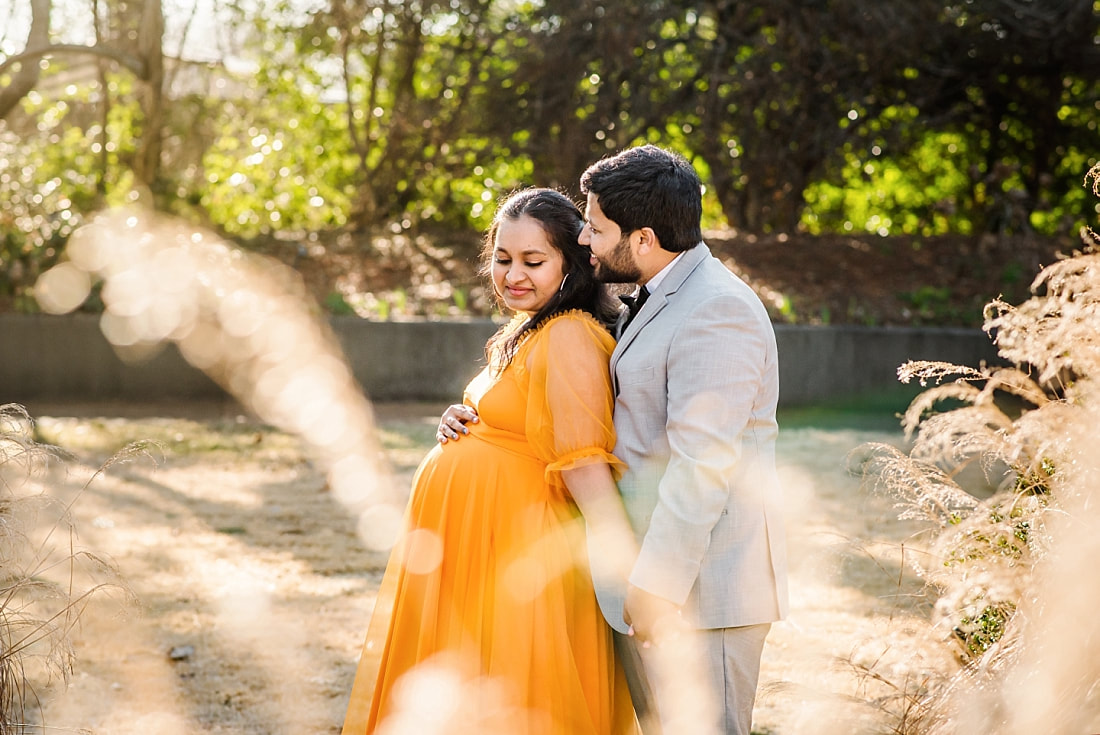 mother and father snuggle during maternity photos at memphis botanic garden