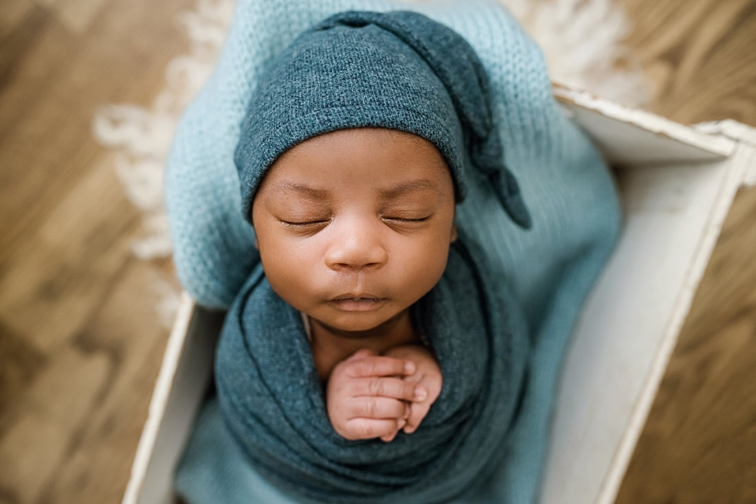 newborn baby wrapped in blue in wooden box for newborn session in Memphis, TN