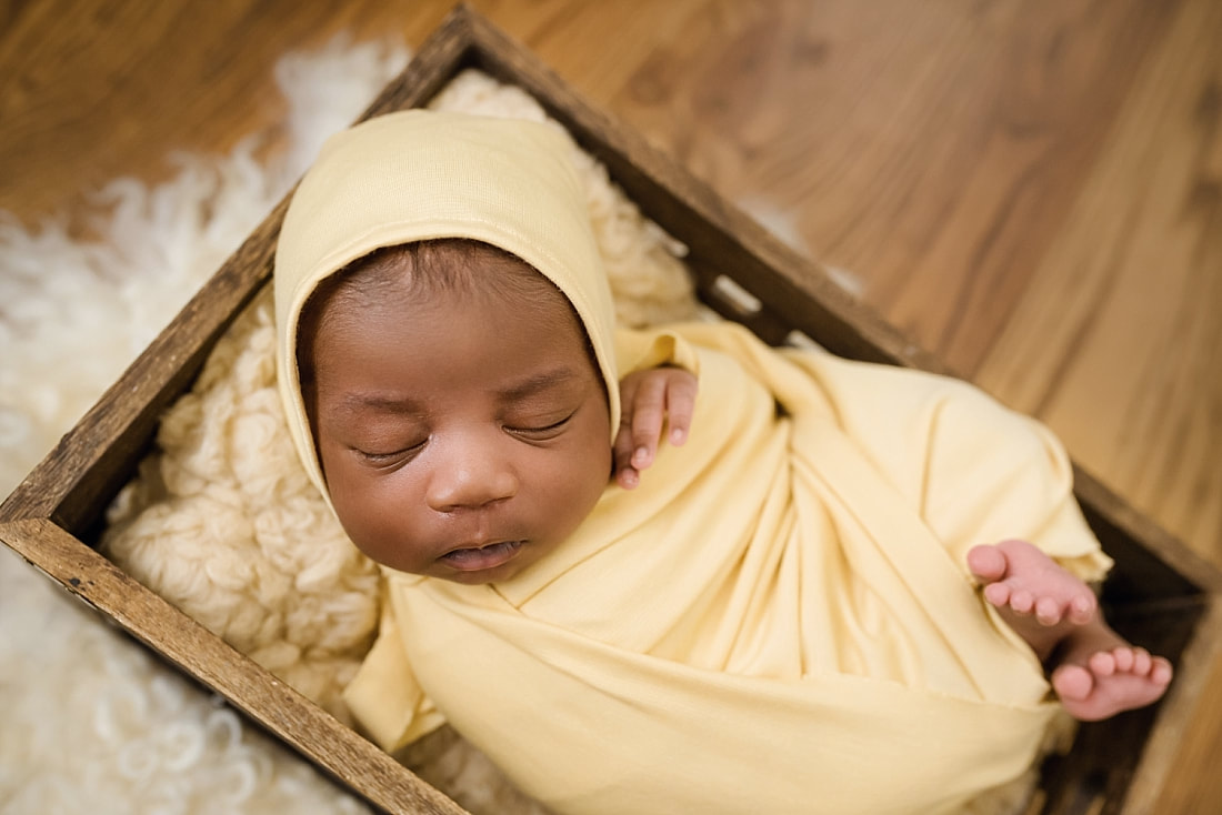 baby wrapped in yellow and sleeping in wooden box for newborn photos in Collierville, TN