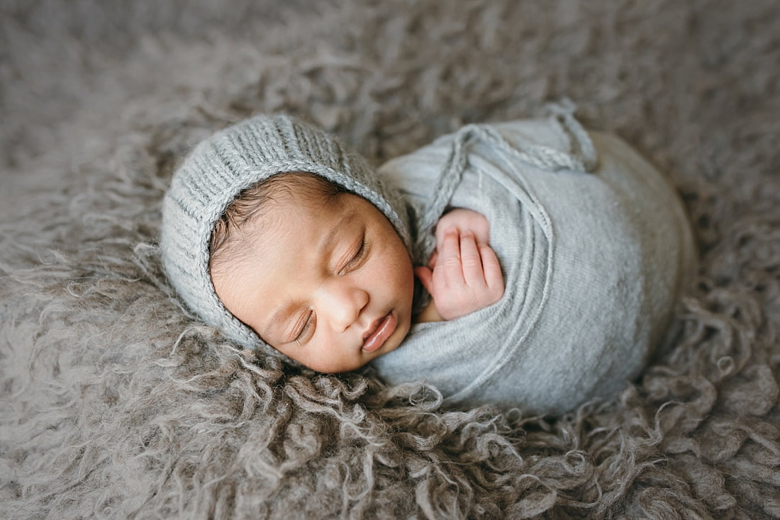 newborn baby boy wearing knit bonnet and swaddled in soft blanket during newborn session in memphis tn