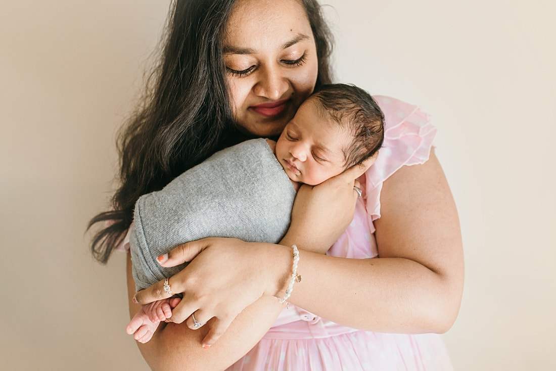 mother smiling down at newborn baby during newborn photos in memphis