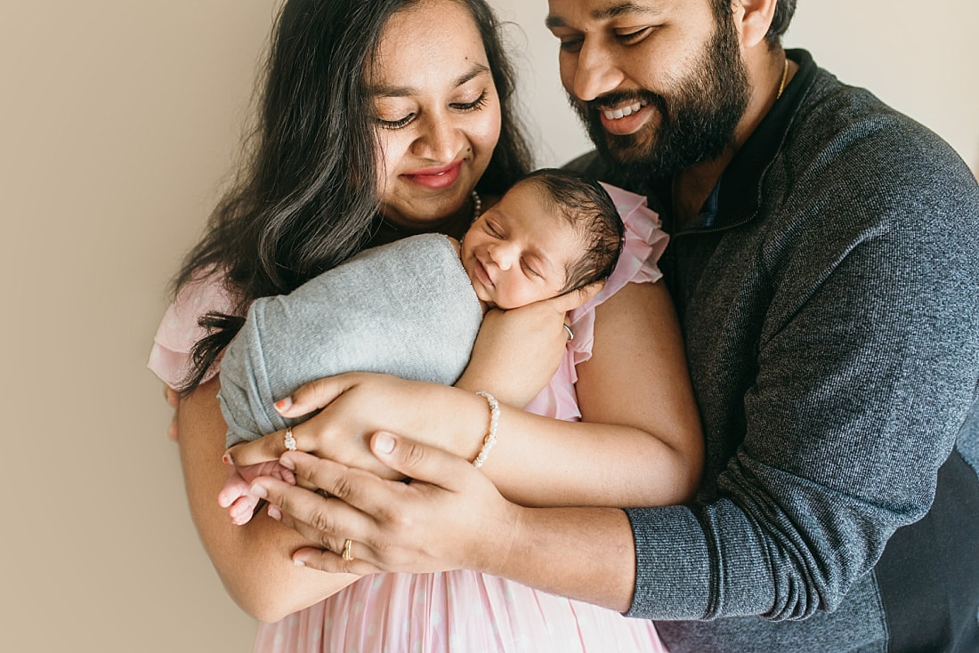 mother and father looking down at smiling baby during newborn photos in memphis